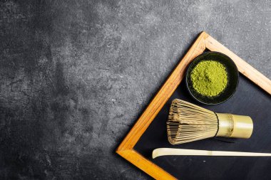 Siyah kasede kibrit yeşil çay tozu ve siyah bir masada kaşık ile geleneksel bambu fırçası çırpışı. Uyuşan yeşil çay yapmak için aksesuarlar. Uzayı kopyala Üst görünüm