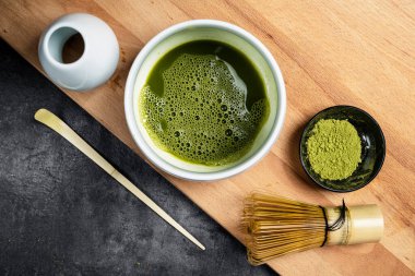 Siyah kasede kibrit yeşil çay tozu ve masada kaşık olan geleneksel bambu fırçası çırpıcısı. Uyuşan yeşil çay yapmak için aksesuarlar. Üst görünüm