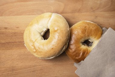 Tahta tahtanın üzerindeki kahverengi kese kağıdındaki simit ekmeğinin yakın görüntüsü. Üst görünüm