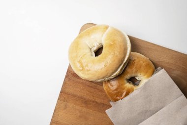 Beyaz arka planda tahtadan izole edilmiş tahtadan yapılmış kahverengi kağıt torbadaki simit ekmeklerinin yakın görüntüsü. Üst görünüm