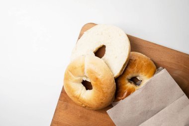 Beyaz arka planda tahtadan izole edilmiş tahtadan yapılmış kahverengi kağıt torbadan dilimlenmiş simit ekmeklerinin yakın görüntüsü. Üst görünüm