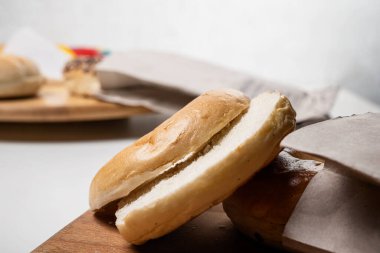 Tahta tahtadaki kahverengi kağıt torbadan kesilen simit ekmeğinin beyaz arka plandaki yakın görüntüsü