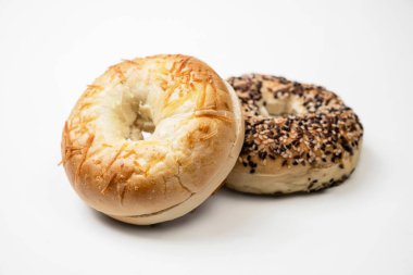 Beyaz zemin üzerinde farklı türde izole edilmiş iki simit ekmeğinin yakın görüntüsü