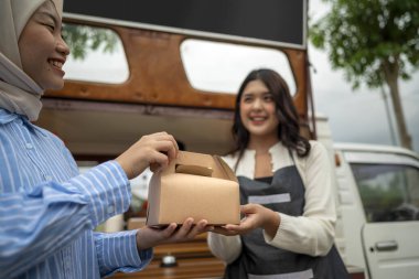 Endonezyalı güneydoğu Çinli bayan garson Çinli Müslüman kadın müşteriye yemek servisi yapıyor. Kamyonda küçük bir işletme.