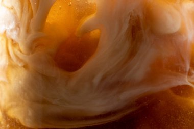 Sütün bardaktaki buzlu kahveye döküldüğü yakın çekim görüntüsü.