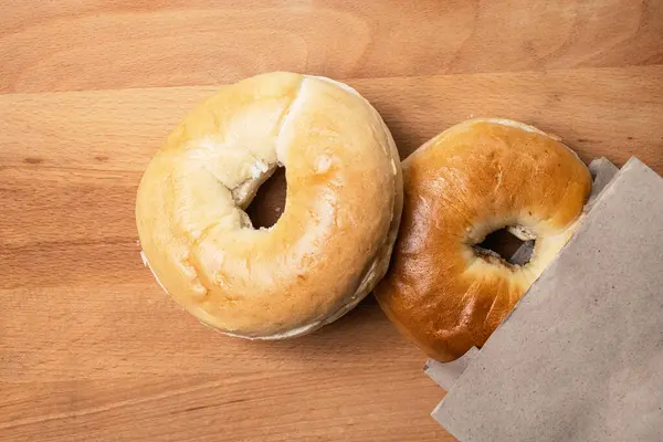 Tahta tahtanın üzerindeki kahverengi kese kağıdındaki simit ekmeğinin yakın görüntüsü. Üst görünüm