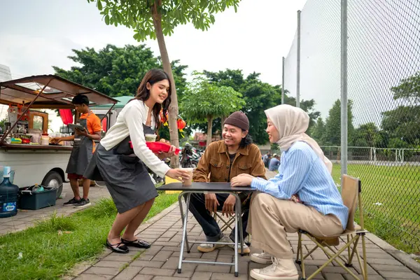 Endonezyalı güneydoğu Asyalı bayan garson Çinli Müslüman kadın ve erkek müşterilere yiyecek ve içecek servisi yapıyor. Kamyonda küçük bir işletme.