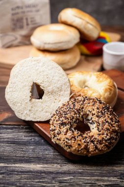 Ahşap bir tahtanın üzerinde dilimlenmiş bagel ekmeği ile çeşitli simit ekmeklerinin yakın görüntüsü