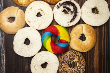 Tahta bir tahtanın üzerinde dilimlenmiş simit ekmeği ile çeşitli simit ekmeklerinin yakın görüntüsü. Üst görünüm