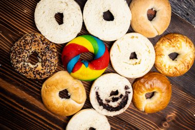 Tahta bir tahtanın üzerinde dilimlenmiş simit ekmeği ile çeşitli simit ekmeklerinin yakın görüntüsü. Üst görünüm