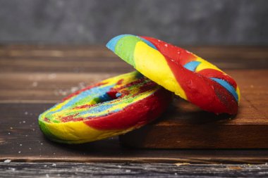 Ahşap bir tahtanın üzerinde gökkuşağı simit ekmeğinin yakın görüntüsü