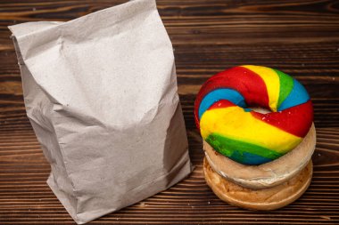 Muhtelif ekmeklerden oluşan bir yığın ve tahta bir tahtanın üzerinde kahverengi bir kese kağıdı.