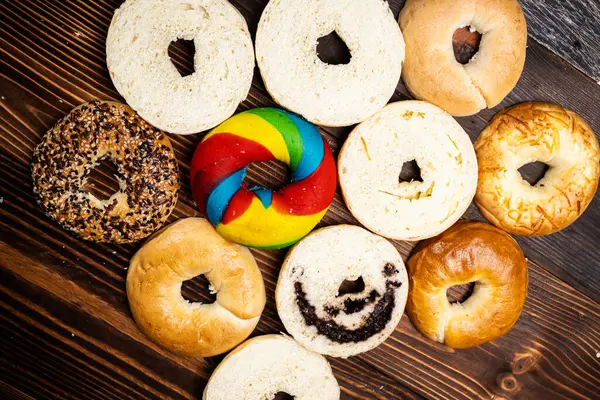 Tahta bir tahtanın üzerinde dilimlenmiş simit ekmeği ile çeşitli simit ekmeklerinin yakın görüntüsü. Üst görünüm