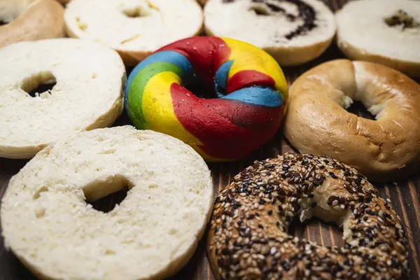 Ahşap bir tahtanın üzerinde dilimlenmiş bagel ekmeği ile çeşitli simit ekmeklerinin yakın görüntüsü