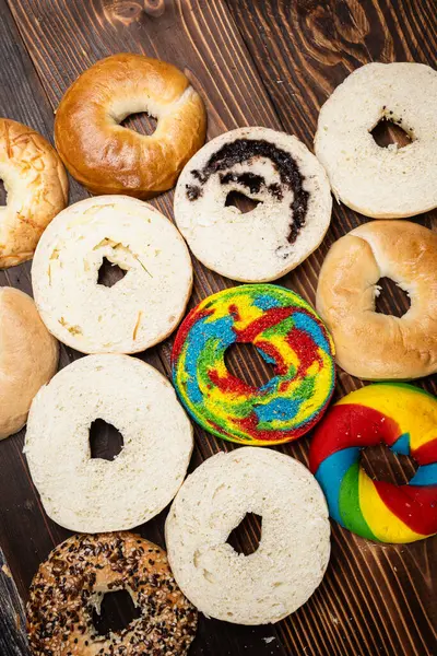 Tahta bir tahtanın üzerinde dilimlenmiş simit ekmeği ile çeşitli simit ekmeklerinin yakın görüntüsü. Üst görünüm