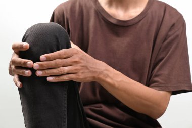 Beyaz bir arka planda, bacağında ağrı olan bir adamın portresi. Sağlık hizmetleri kavramı