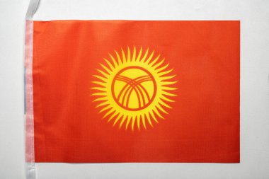 Kırgızistan ulusal bayrağının beyaz arka planda izole edilmiş yakın görüntüsü. Hükümet ve milliyet kavramı