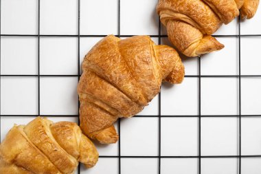 Soğutma tepsisinde taze pişmiş kruvasan ve beyaz bir arka plan. Üst görünüm