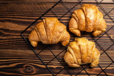 Ahşap zeminli soğutma tepsisinde taze pişmiş kruvasanlar. Üst görünüm