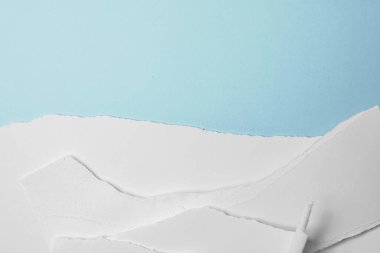 Mavi arka planda yırtılmış beyaz kağıt yığını. Boşluğu kopyala