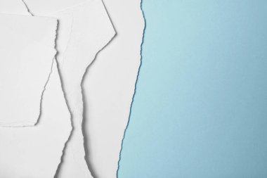 Mavi arka planda yırtılmış beyaz kağıt yığını. Boşluğu kopyala