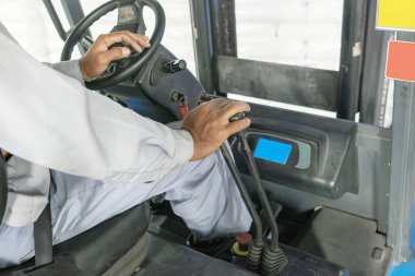 İşçi operatörü depodaki bir forklifti kontrol ediyor. Depolama, envanter, endüstri ve lojistik