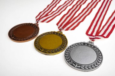 Beyaz arka planda izole edilmiş kırmızı ve beyaz şeritli bir şeritten asılı bronz, gümüş ve altın madalya setleri. Uzayı kopyala Başarı, tanınma veya rekabetin sembolü