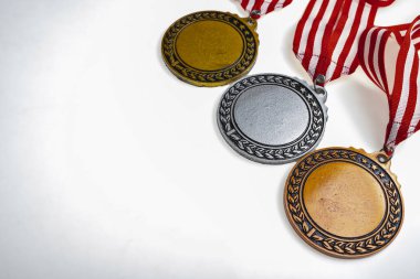 Beyaz arka planda izole edilmiş kırmızı ve beyaz şeritli bir şeritten asılı bronz, gümüş ve altın madalya setleri. Uzayı kopyala Başarı, tanınma veya rekabetin sembolü