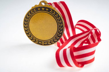 Beyaz arka planda izole edilmiş kırmızı ve beyaz şeritli bir şeritten asılı duran altın madalyanın yakın görüntüsü. Uzayı kopyala Başarı, tanınma veya rekabetin sembolü