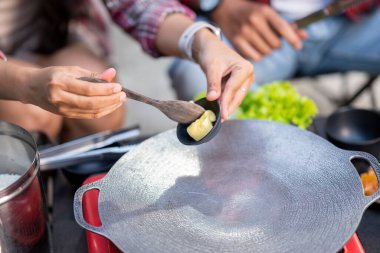İnsanların portatif bir fırının üzerinde tereyağını erittiği yakın çekim görüntüsü. Doğal ortamdaki yemekten zevk alma sahnesi.
