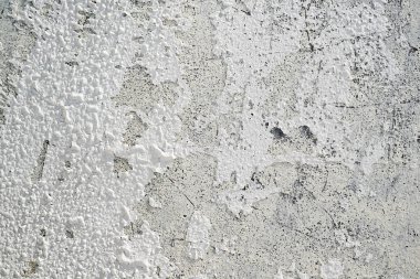 Yüksek desenli beyaz beton duvarın yakın görüntüsü. Yüzeyi eski ve soyulmuş boyayla yıpranmış. Soyut arkaplan
