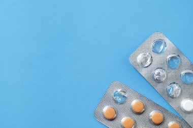 Mavi arka planı olan su toplayan bir pakette ilaç haplarının yakın görüntüsü. Sağlık ve İlaç kavramı