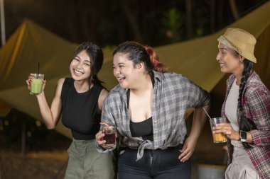 Endonezyalı güneydoğu Asyalı bir grup kadın açık havada dinleniyor ve serinletici içeceklerin tadını çıkarıyor. Doğal ortamdaki yemekten zevk alma sahnesi.