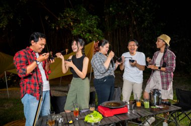 Endonezya 'nın güneydoğusundaki Asyalılar yemek yiyorlar, yemek çubuklarını kullanarak kendilerine küçük siyah kaselerden ızgara yemek servis ediyorlar. Doğal ortamdaki yemekten zevk alma sahnesi.