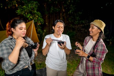 Endonezya 'nın güneydoğusundaki Asyalılar yemek yiyorlar, yemek çubuklarını kullanarak kendilerine küçük siyah kaselerden ızgara yemek servis ediyorlar. Doğal ortamdaki yemekten zevk alma sahnesi.