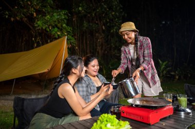 Endonezyalı güneydoğu Asyalı kadın kamp yaparken diğerlerine pilav servis etti. Doğal ortamdaki yemekten zevk alma sahnesi.
