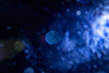 Yumuşak, koyu mavi bokeh ışıkları içeren soyut bir arka plan. Dekoratif öge arkaplan olarak kullanmak için uygun