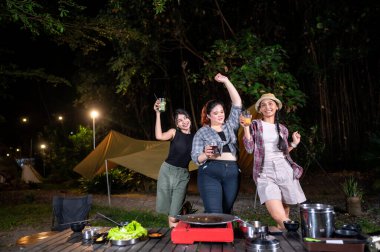 Endonezyalı güneydoğu Asyalı kadınlar birlikte dışarıda dinleniyor ve içeceklerin tadını çıkarıyorlar. Doğal ortamdaki yemekten zevk alma sahnesi.