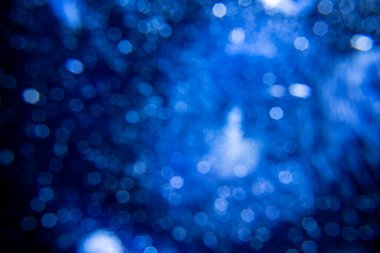 Yumuşak, koyu mavi bokeh ışıkları içeren soyut bir arka plan. Dekoratif öge arkaplan olarak kullanmak için uygun