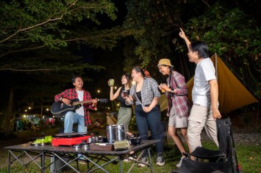 Endonezya 'nın güneydoğusundaki Asyalılar ferahlatıcı içeceklerin tadını çıkarıyorlar. Bir tanesinin elinde akustik gitar var. Yemekten zevk alma yaşam tarzının doğal bir manzarası