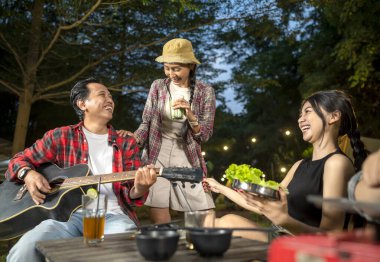 Endonezyalı güneydoğu Asyalılar ızgara tavada marine edilmiş et bulgogi pişiriyorlar. Bir tanesinin elinde akustik gitar var. Yemekten zevk alma yaşam tarzının doğal bir manzarası