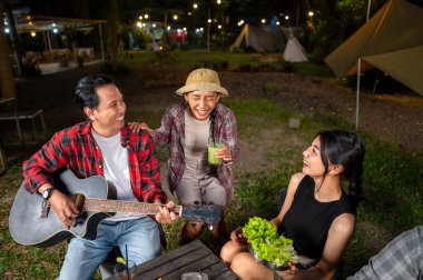 Endonezyalı güneydoğu Asyalılar ızgara tavada marine edilmiş et bulgogi pişiriyorlar. Bir tanesinin elinde akustik gitar var. Yemekten zevk alma yaşam tarzının doğal bir manzarası