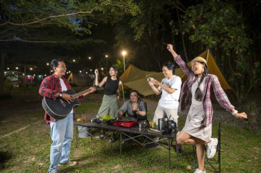 Endonezyalı güneydoğu Asyalılar ızgara tavada marine edilmiş et bulgogi pişiriyorlar. Bir tanesinin elinde akustik gitar var. Yemekten zevk alma yaşam tarzının doğal bir manzarası