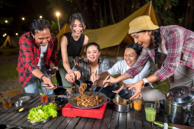 Endonezyalı güneydoğu Asyalılar ellerinde çubuklarla soğanlı ızgara tavada marine edilmiş et bulgogi pişiriyorlar. Doğal ortamdaki yemekten zevk alma sahnesi.