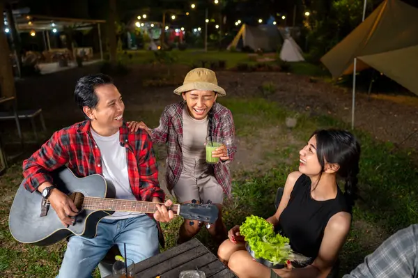 Endonezyalı güneydoğu Asyalılar ızgara tavada marine edilmiş et bulgogi pişiriyorlar. Bir tanesinin elinde akustik gitar var. Yemekten zevk alma yaşam tarzının doğal bir manzarası