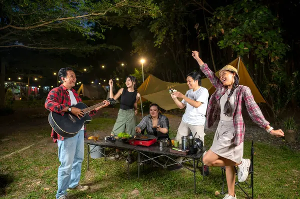 Endonezyalı güneydoğu Asyalılar ızgara tavada marine edilmiş et bulgogi pişiriyorlar. Bir tanesinin elinde akustik gitar var. Yemekten zevk alma yaşam tarzının doğal bir manzarası