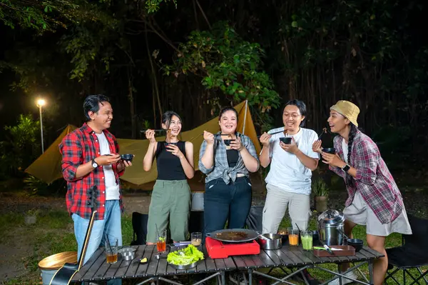 Endonezya 'nın güneydoğusundaki Asyalılar yemek yiyorlar, yemek çubuklarını kullanarak kendilerine küçük siyah kaselerden ızgara yemek servis ediyorlar. Doğal ortamdaki yemekten zevk alma sahnesi.