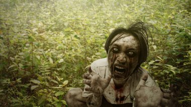 Lanetli ormandaki çalıların altında yaralı ve kanlı saklanan korkunç erkek zombi. Sahne korkutucu ve ürkütücü. Dramatik duman ya da sis etkisi. Ürkütücü Cadılar Bayramı kavramı