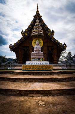 Chachoengsao, Tayland, 28 Temmuz 2023. Wat Nong Rua, Buda 'nın beyaz heykeli beyaz çatılı tahta bir tapınağın önünde meditasyon pozisyonunda oturuyordu. Tapınak ağaçlar ve çiçeklerle çevrili..