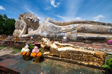 Tayland 'ın Ayutthaya kentindeki antik kalıntıların arasında huzur içinde uzanan görkemli bir Buda heykeli bulunuyor. Buda 'nın dingin ifadesi ve çevreleyen doğal güzellik dinginlik ve ruhsal bağlantı hissi yaratıyor..